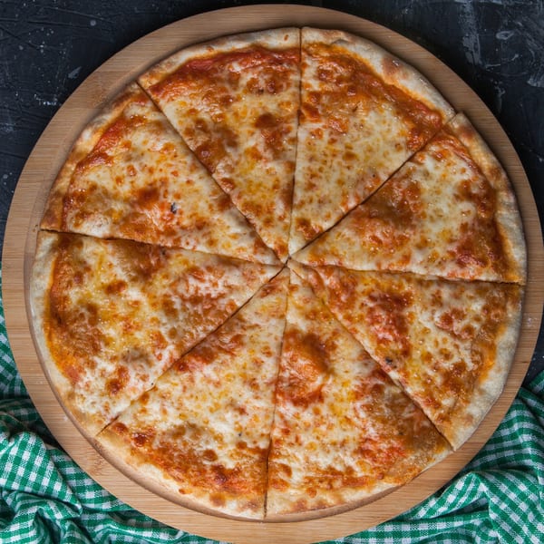 A whole cheese pizza from The Village Pizza, sliced into eight pieces on a wooden board.